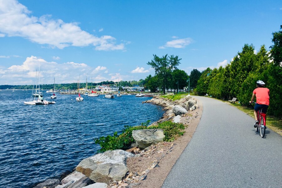 Cyclist riding the lakeside path past moored sailboats on Lake Champlain, Burlington, Vermont