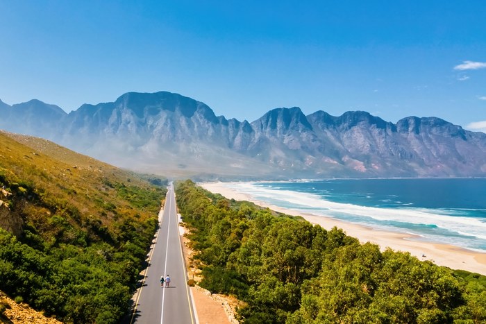 Coastal road on South Africa's Garden Route running between mountains and a sandy beach at Kogel Bay