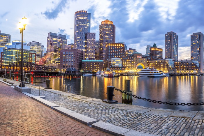 Boston Harbor skyline at dusk, viewed from the waterfront promenade near the site of the Boston Tea Party.